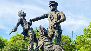 Statue of an officer grabbing a child while holding the leash of an aggressive police dog