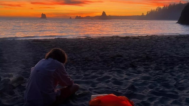 David sitting on a beach at sunset