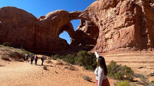 Visitor pointing at a geological arch formation