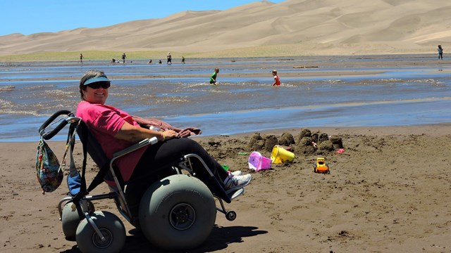 Visitor in a wheelchair at a sand dunes beach