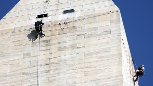 Engineers in climbing equipment inspecting the top of the Washington Monument 