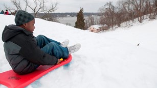 Kid perched to sled down a hill