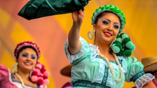 Closeup view of dancers in colorful dresses coming to celebrate the Golden Gate Bridge.