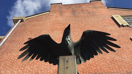 Statue of a raven next to a brick building