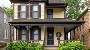 Two story yellow house with brown trim