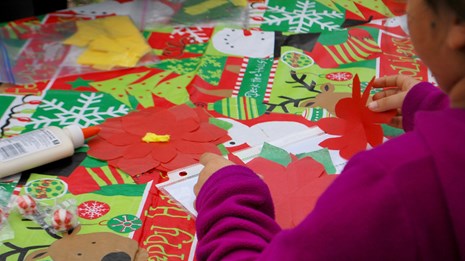 Person working at a craft table covered in colorful paper