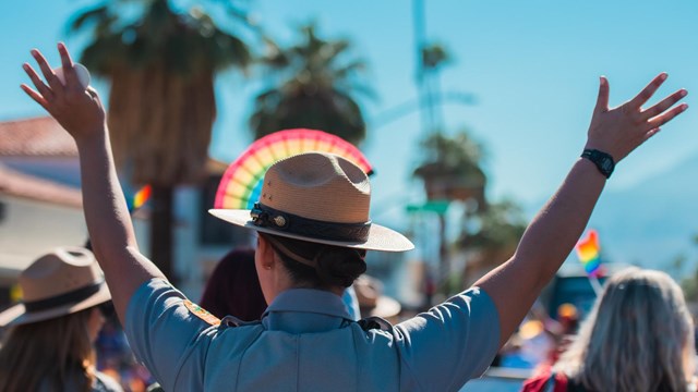 Back of a ranger with their ranger hat lined up with a decorative rainbow