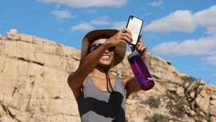 Young woman in the desert holding her phone up