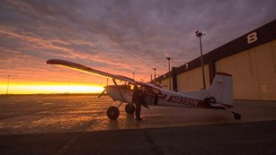 Plane outside of a hangar during sunset