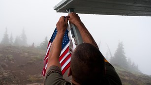 Volunteer handing a US flag on a porch