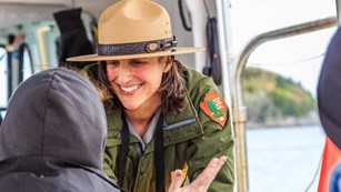 A park ranger speaks with a visitor on a summer boat program.