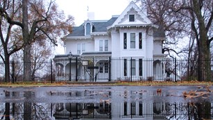 Three-story white house and reflection in a pond