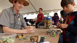 Park ranger and young boy studying toy bison figure