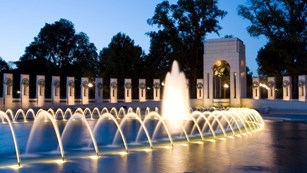 Memorial pillars surrounding a large fountain at night