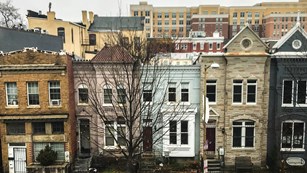 A row of townhouses in front of rows of modern buildings