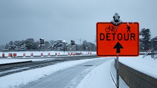 Detour sign in front of snow and ice covered road