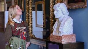 Visitor looking at a bust and paintings of suffragists