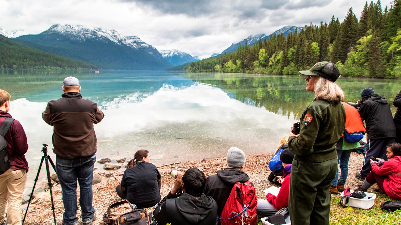 Group of students with ranger sit looking for loons at Bowman Lake