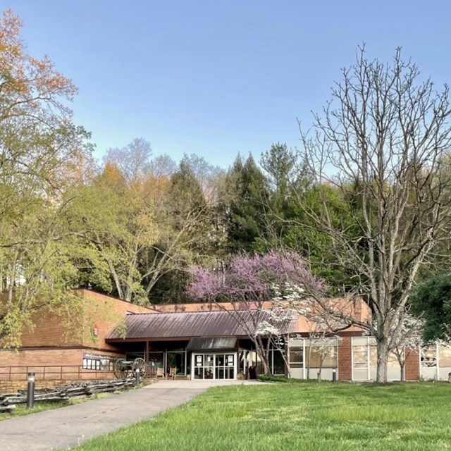 modern building with glass windows surrounded by trees.