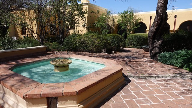 A fountain surrounded by a stone patio in a courtyard garden at Tumacácori National Historical Park