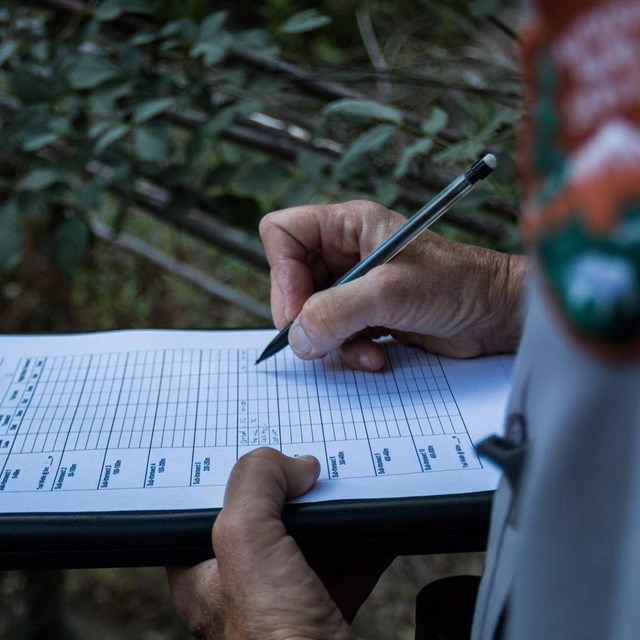 An NPS employee writes on a clipboard