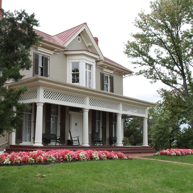 Flowers surround the foundation of the two-story house at Cedar Hill