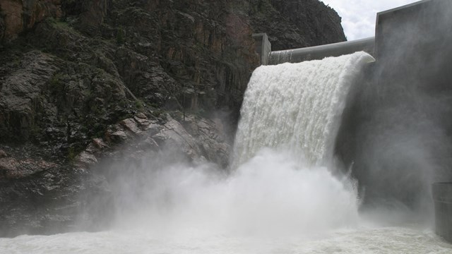 Water cascades from an open spillway on a concrete dam