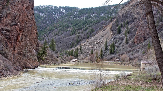 A small dam and river between two canyon walls