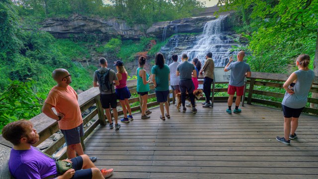 A crowd of people look at a waterfall.