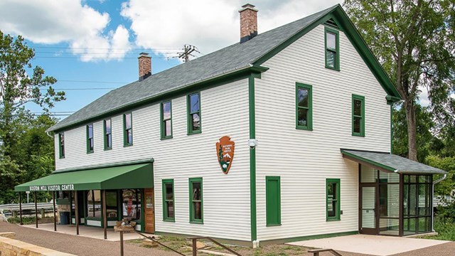 A photo of the exterior of Boston Mill Visitor Center, a white building with green trim