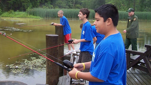 A group of kids fish off a pier.