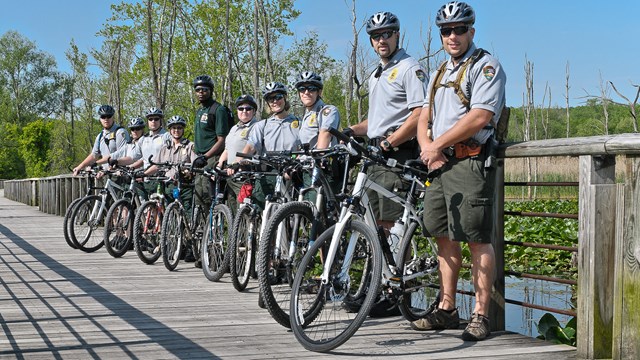 Law Enforcement Rangers line the boardwalk with their bicycles and helmets. 