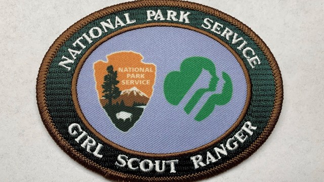 Blue and green patch with NPS and GSUSA logos; words read "National Park Service, Girl Scout Ranger"