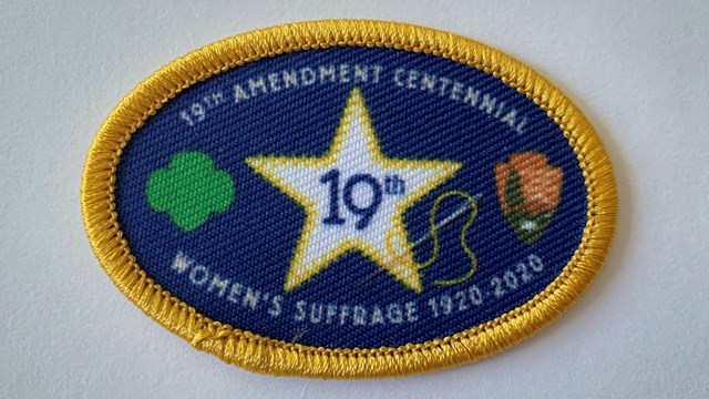 Blue and gold patch with NPS, GSUSA logos and white star; words read "19th Amendment Centennial".