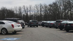 A gray minivan navigates a crowded parking lot