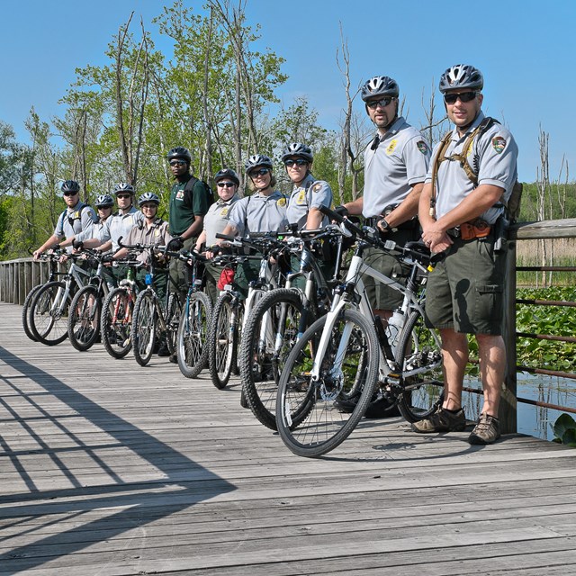 Law Enforcement Rangers line the boardwalk with their bicycles and helmets. 