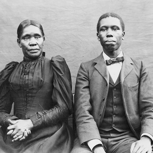 A man and a woman sit in chairs next to one another.