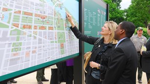 A woman points on a large outdoor map.