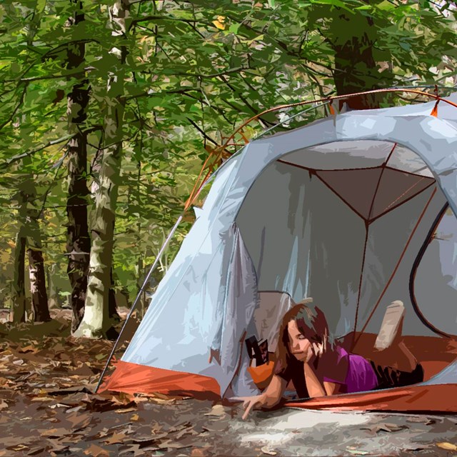 A girl rests on her elbows in a tent in the woods.