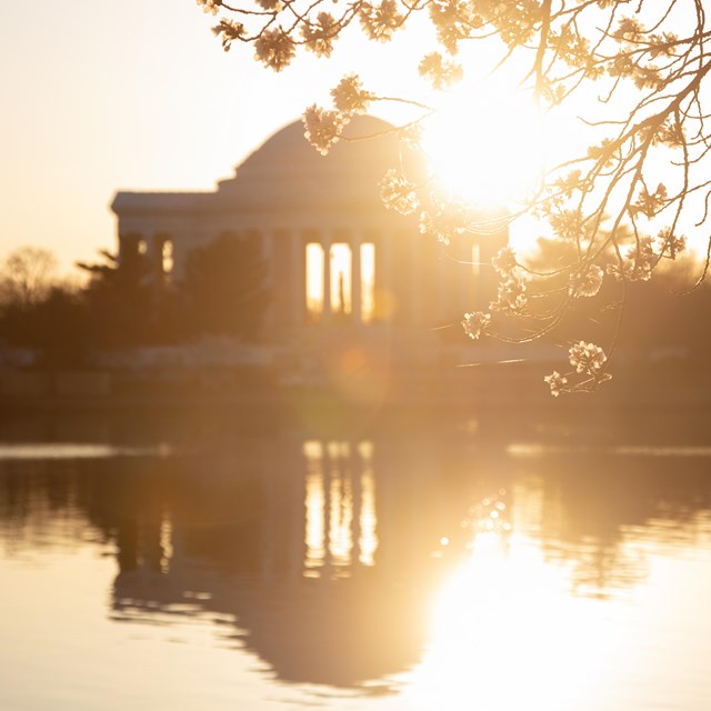 Sunrise over the Thomas Jefferson Memorial reflects off the water in the Tidal Basin.