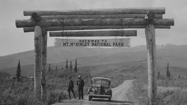 historic photo of people standing under a sign for the Mt. McKinley National Park