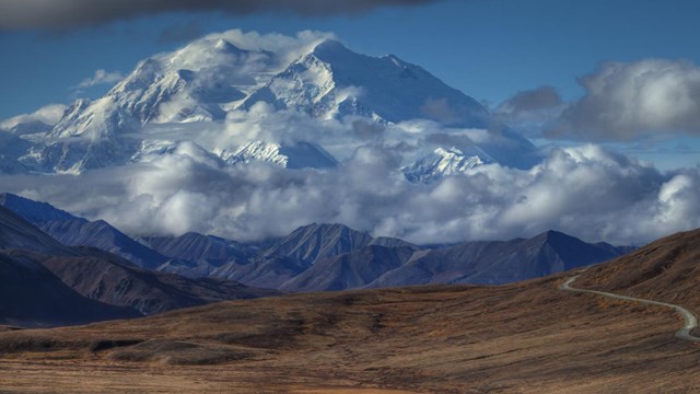 a tall snow-capped mountain peaking out of the clouds