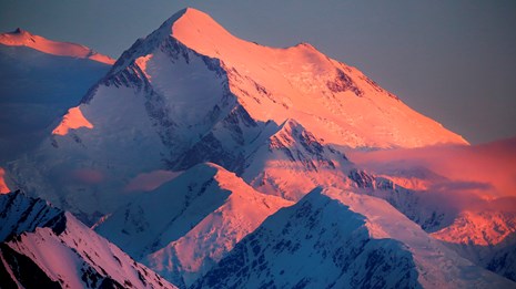 a huge snowy mountain tinged pink by a setting sun