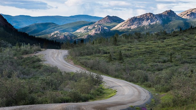 a dirt road winding through brushy hills and mountains