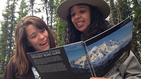 a ranger uses a book to describe geology to a visitor