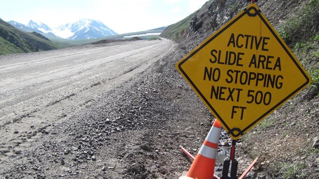 a sign indicates an active slide area and requests that traffic does not stop