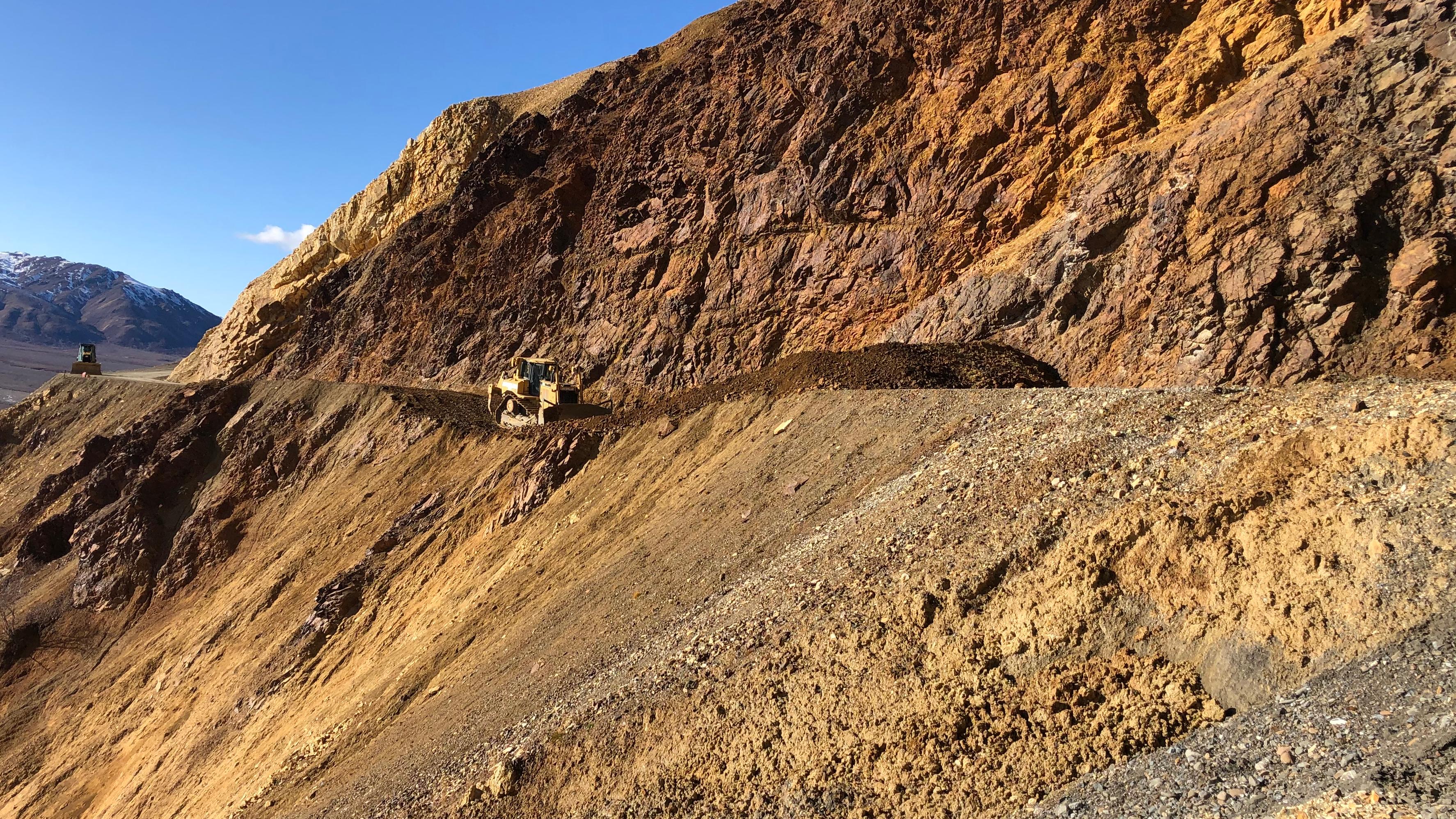 a steep mountainside of bare orange, yellow, and brown rock