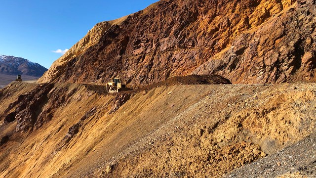a steep mountainside of bare orange, yellow, and brown rock