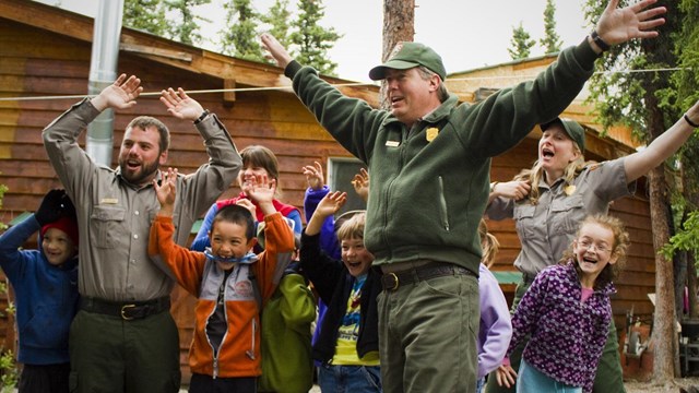 A group of campers and rangers wave their arms above their heads 