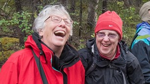 two women laugh while out on a hike in the woods